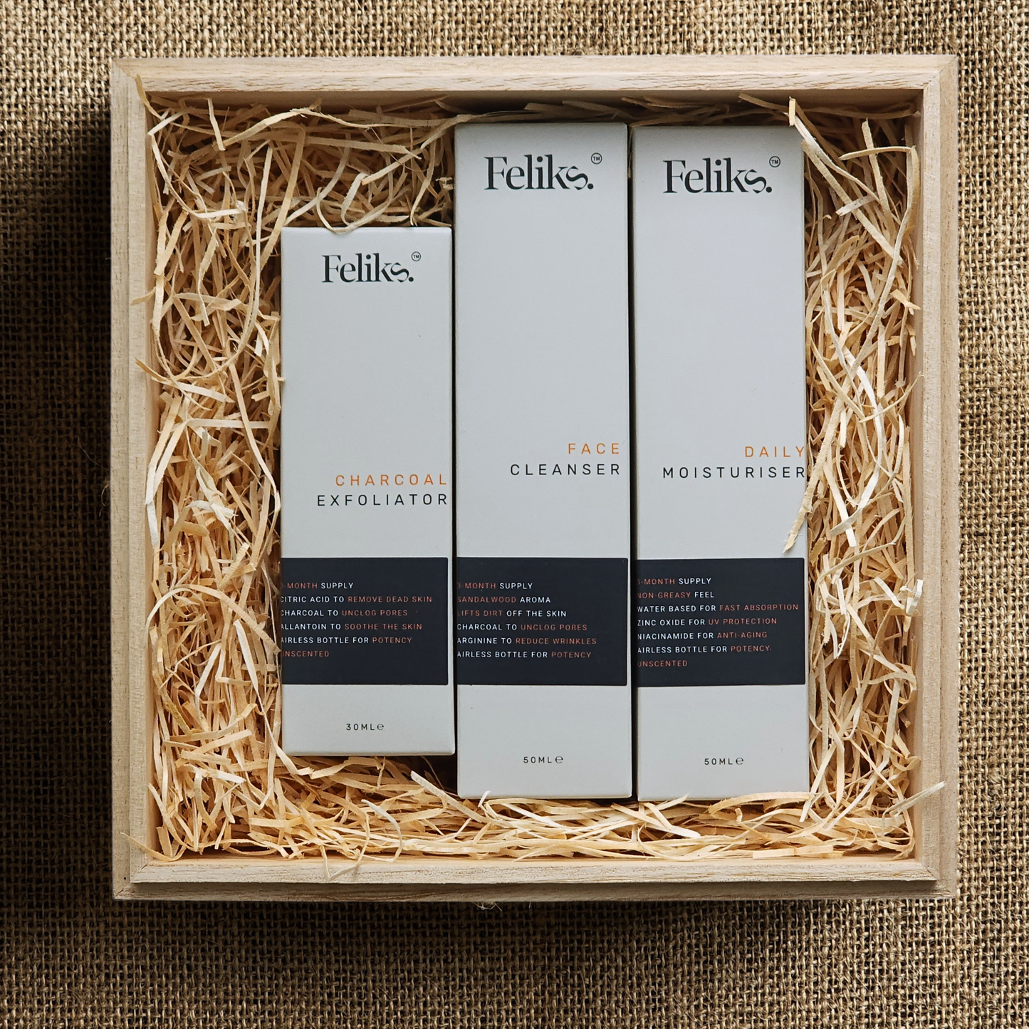 wooden gift box for men opened with daily moisturiser +spf, anti-aging face cleanser, chemical exfoliator inside. feliks skincare